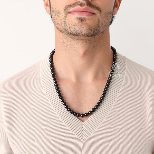 Black bead necklace on man from different angle