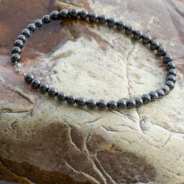 Shungite bead necklace resting on stone outdoors